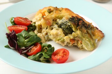 Tasty vegetable casserole and salad on white wooden table, closeup