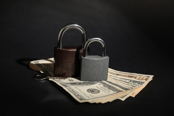 Padlocks with money and key on black background