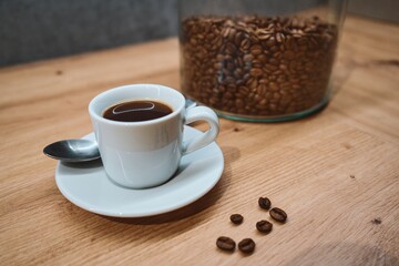 Minimalist Cup of Black Coffee with Beans on Wooden Table