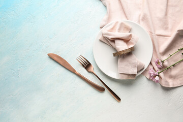 Stylish table setting with beautiful flowers on light blue background