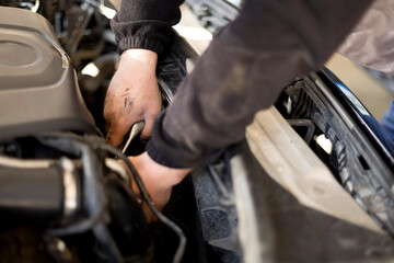 Auto mechanic working on car engine in his mechanic garage. Repair service. close up