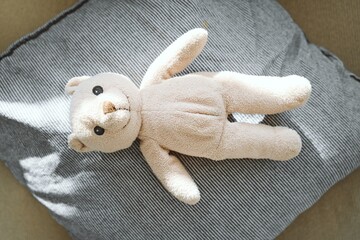 Soft Beige Teddy Bear Resting on Striped Pillow in Sunlight