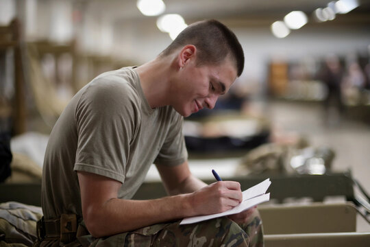 Young soldier writes in barracks while reflecting on military life and experiences during training