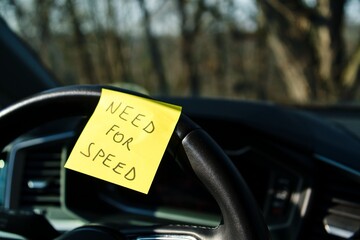 Sticky note with 'Need for Speed' on car steering wheel