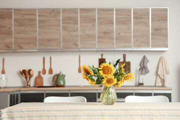 Vase with sunflowers on dining table in kitchen