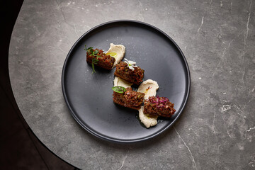 Exquisite presentation of gourmet beef tartare topped with herbs and flowers on smoked mayonnaise, food styling concept