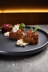 Gourmet appetizer, rye bread pieces with flavorful toppings, garnished creatively, served elegantly on black plate, fine dining concept