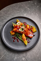 Gourmet Grilled Salmon with Citrus and Pomegranate Garnish on Dark Plate, Elegant Food Presentation Concept