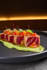 Seared tuna slices with avocado puree and microgreens on black plate gourmet dining presentation concept