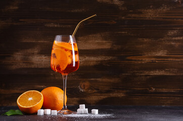 Glass of Aperol spritz cocktail with fruits and sugar on black table