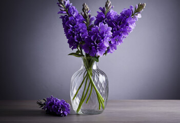 The close-up background of purple flowers in the vase on the table is grey
