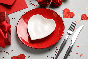 Beautiful table setting with gift box, envelope and red roses on grey background. Valentine's Day celebration