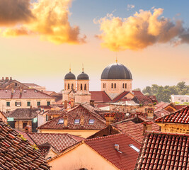 Fototapeta premium beautiful old city sunset landscape with ren and orange tile roofs of houses and nice cathedral church in traditional venetian style with bell tower and chapel and evening sky on background
