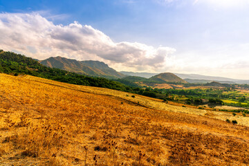 Obraz premium panoramic farmland view of yellow field with sceniv valley , mountains and amazing cloudt sunset