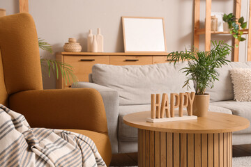Interior of stylish living room with cozy brown armchair, grey sofa and houseplant on wooden coffee table