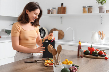 Young woman with compost bin during cooking in kitchen