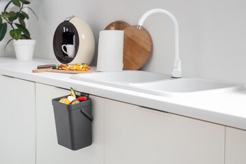 Compost bin with vegetable scraps in kitchen