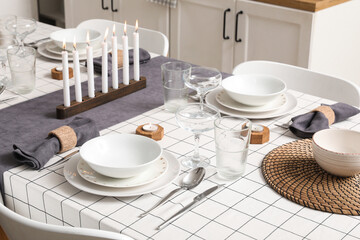 Festive table setting with burning candles in kitchen. Closeup