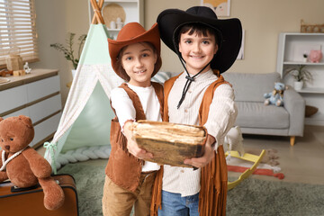 Cute children dressed as cowboys with adventure book at home