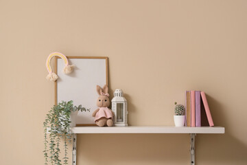 Shelf with plants, toys and books on beige wall
