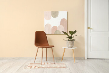Chair, houseplant on coffee table and picture on beige wall in room