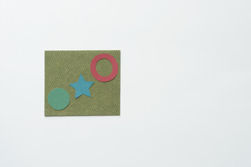 circle, star, and ring shapes on a green card and blank paper