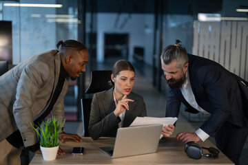 Business professionals discussing documents in a modern office. Concept of teamwork, corporate collaboration, leadership, business strategy, and decision-making in a workplace
