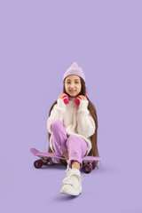 Stylish girl in hat with headphones sitting on skateboard against lilac background