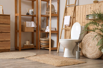 Interior of restroom with toilet bowl, ladder and shelf units