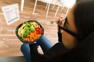 POV of woman eating fresh salad while wearing AR glasses, displaying nutritional data through...