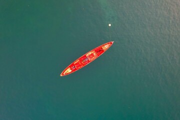 Aerial view of a solitary red boat floating on calm, deep blue water near Sao Tome and Principe
