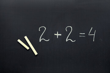 Yellow chalks with drawn mathematical statement on blackboard