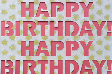 decorative Happy Birthday banner sign machine-cut from decorative scrapbooking paper on pink paper