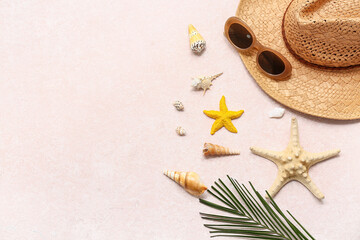 Summer hat with sunglasses, palm leaf and sea shells on pink grunge background