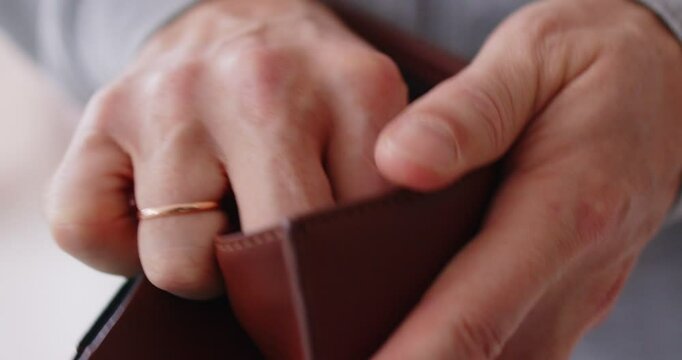 Close-up shot of a poor man opening an empty wallet, without money. Financial struggles, poverty, and the impact of bankruptcy on budget and banking situation, highlighting economic hardships.