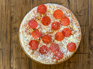 A Frozen Meat Pizza Before Cooking On A Wooden Table