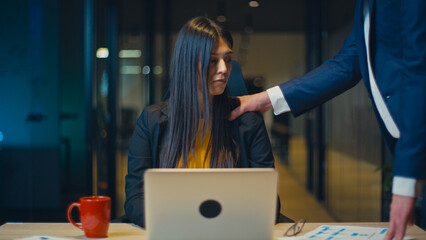 Professional woman in an office looks uncomfortable as a male colleague places his hand on her...