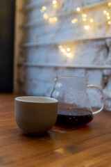 Warm coffee cup beside a glass carafe in a cozy cafe setting