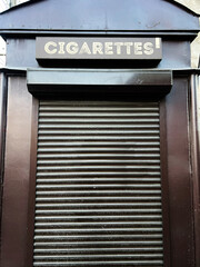 Obraz premium Closed rolling shutter kiosk with cigarettes sign on top viewed closely.