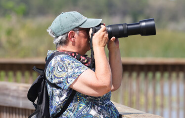 Woman looking through a camera viewfinder with an extended lens.