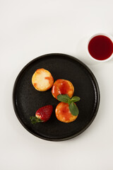 Breakfast cheese cottage pancakes beries and jam on black plate