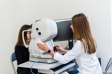 Eye exam by optometrist. A professional is conducting an eye exam for a patient using advanced equipment in a modern clinic setting.