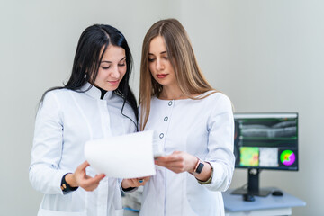 Doctors review patient reports. Two female medical professionals review patient reports in a...