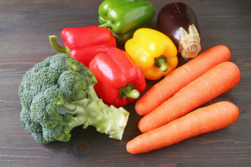 Heap of multi-color assorted fresh vegetables scattered on black wooden background