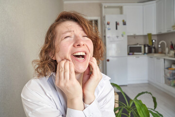 Joyful young caucasian female laughing enthusiastically in modern kitchen setting.