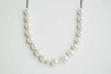 Obraz premium Elegant Pearl Necklace: Exquisite strand of pearls, classic and timeless, hangs gracefully against soft background, emphasizing the necklace's understated beauty and luxurious appeal.