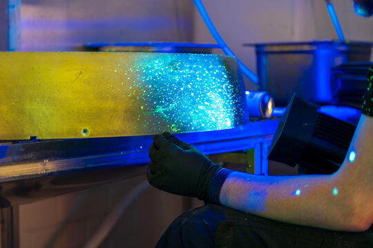 Industrial FPI testing showing fluorescent indications under blacklight examination. Non-destructive testing method revealing surface discontinuities with penetrant inspection