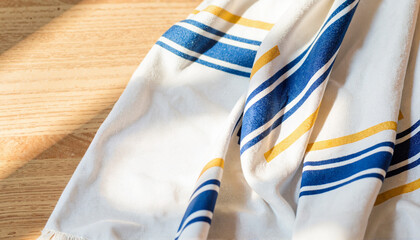 Traditional prayer shawl draped on wooden surface, spiritual symbolism