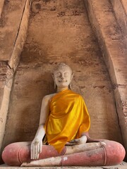 A serene Buddha statue draped in a golden robe, set against a rustic stone backdrop, symbolizing peace and spirituality.
