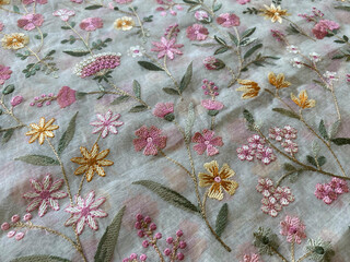 Delicate pastel threads intertwine to form intricate floral patterns, each petal and leaf meticulously detailed.